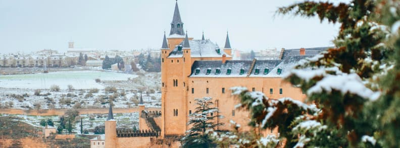 Vue du chateau de Segovie sous la neige avec campagne hivernale en arriere plan.