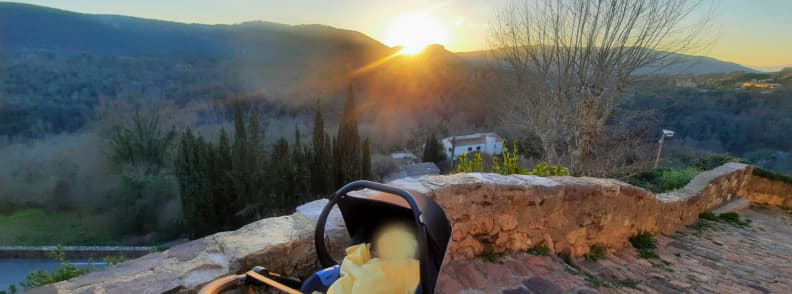 Coucher de soleil Bagnols en Foret promenade en famille rue du Portail Bébé installé dans une poussette près d’un muret en pierre au point de vue de la rue du Portail à Bagnols-en-Forêt, face au soleil couchant et aux collines boisées du Var.