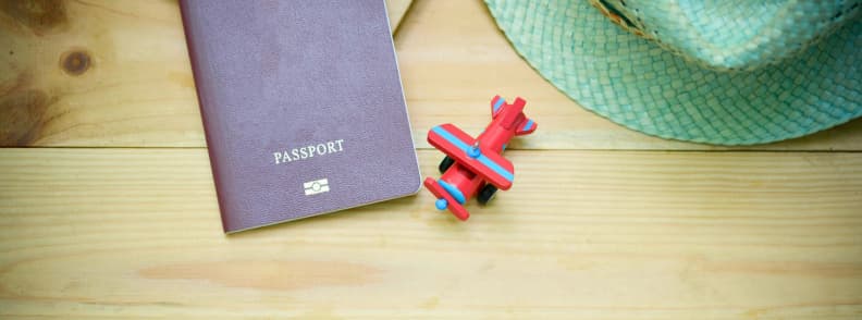 Le passeport d’un enfant à côté d’un avion-jouet et d’un chapeau de soleil, représentant les documents de voyage pour tout-petit, les exigences de passeport, et les lettres de consentement nécessaires pour voler avec un tout-petit.