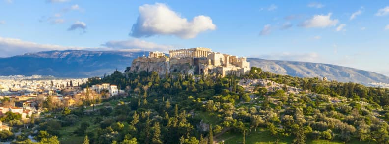 Guide sites archéologiques Athènes. Vue panoramique de l’Acropole Athènes dominant la ville avec le Parthénon et les temples antiques au sommet de la colline sacrée