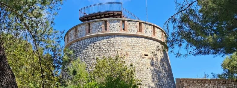 Tour de la Batterie du Graillon au Cap d’Antibes entourée de pins méditerranéens, site historique abritant Posidonia Espace Mer et Littoral.