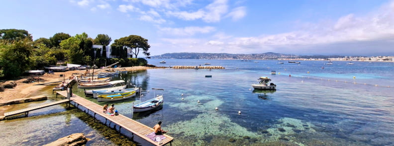 Vue sur le Port de l’Olivette au Cap d’Antibes avec petits bateaux traditionnels, eau cristalline et panorama sur le Golfe Juan à proximité de Posidonia Antibes.