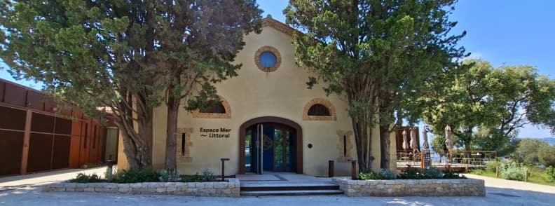 Entrée de Posidonia Espace Mer et Littoral au Cap d’Antibes avec bâtiment historique, terrasse ombragée et accès au musée de la mer Antibes.
