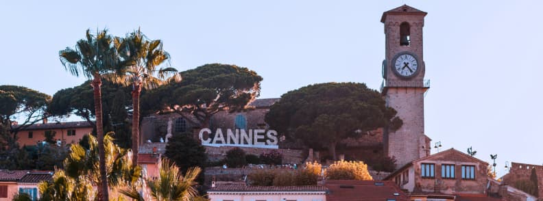 Le Suquet à Cannes en automne, avec la tour de l’horloge, des pins, des palmiers et les toits de la vieille ville sur la Côte d’Azur.