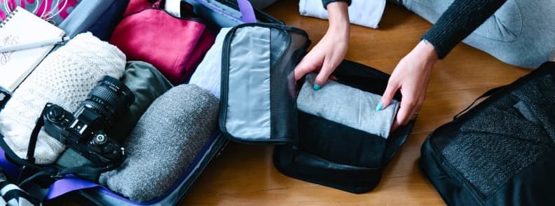 Valise ouverte pour un séjour sur la Côte d’Azur en automne, avec vêtements en couches, appareil photo et organiseurs de voyage.