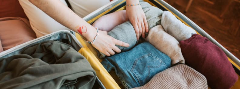Valise ouverte remplie de vêtements pliés pour un séjour en Provence en automne, avec pulls, pantalon et couches adaptées aux températures de septembre à novembre.