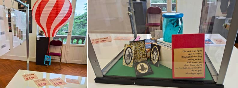 Exposition Le Monde dans la Poche à la Villa Aurélienne à Fréjus, avec une montgolfière miniature rouge et blanche, des cartes photographiques anciennes et des objets présentés sous vitrine.