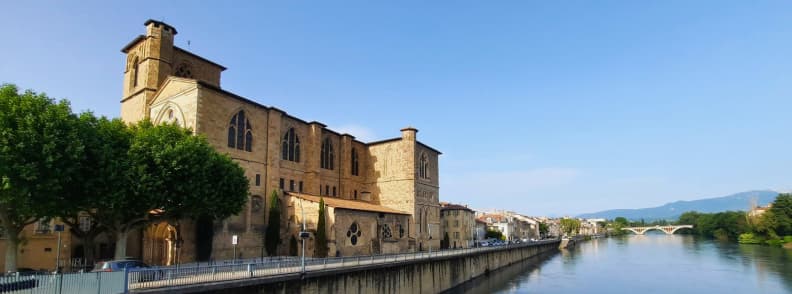 Collegiale Saint Barnard din Romans sur Isere vazuta de pe malul raului Isere cu podul si muntii in departare