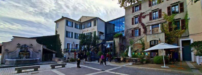 Vedere spre Hotel Lou Calen Cotignac, clădire istorică renovată din Cotignac Provence Verte, cu terasă, restaurant și fântână în piață