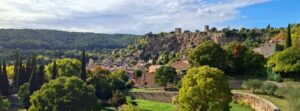 Vizita Cotignac France ghid turistic sat trogloditic Provence Verte Vizita Cotignac France ghid calatorie. Vedere panoramică asupra satului Cotignac Var, cu Rocher de Cotignac, turnurile sarazine și casele provensale înconjurate de verdeață în inima regiunii Provence Verte