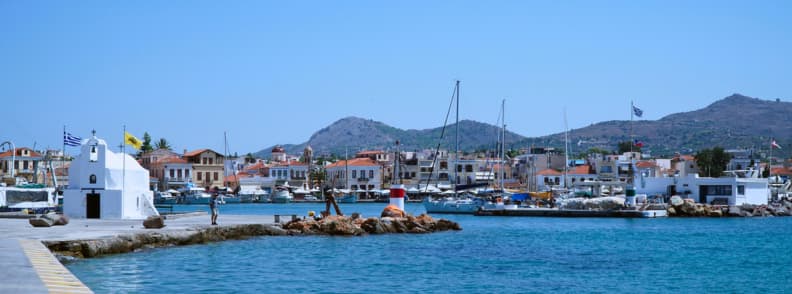 Portul din Egina Grecia cu apă turcoaz, bărci și clădiri tradiționale, parte dintr-o excursie de o zi din Atena
