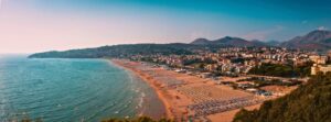 Ghid plaje langa Roma. Plajă întinsă cu nisip și șezlonguri pe coasta Lazio, lângă Roma, mărginită de oraș, dealuri și Marea Tireniană