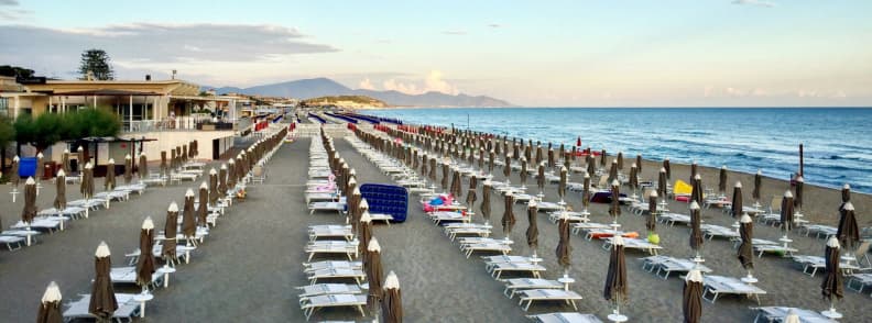 Lido pe plaja Scauri, cu rânduri ordonate de șezlonguri și umbrele închise lângă Marea Tireniană