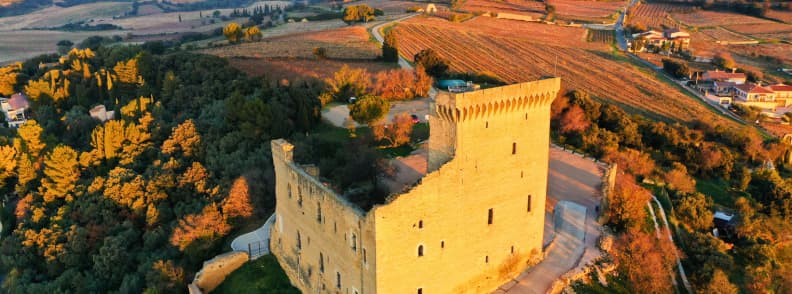 Chateauneuf du Pape Toamna Podgorii Provence Castel Châteauneuf-du-Pape toamna, cu ruinele castelului medieval înconjurate de podgorii și arbori în nuanțe aurii și ruginii din Provence.