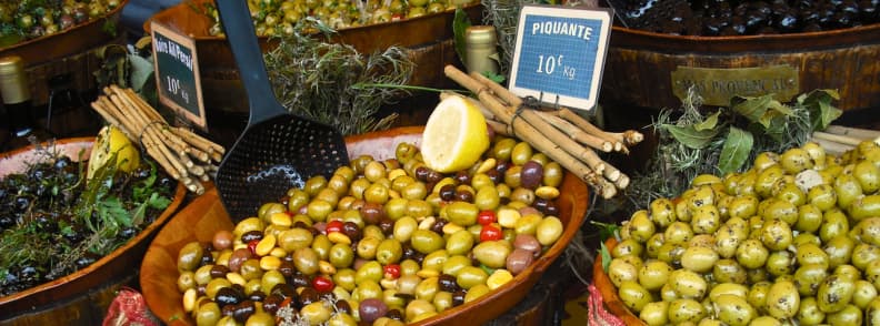 Masline Provence Piata Toamna Produse Locale Măsline verzi și negre condimentate expuse la o piață din Provence, cu lămâie, ierburi aromatice și prețuri afișate pe kilogram.