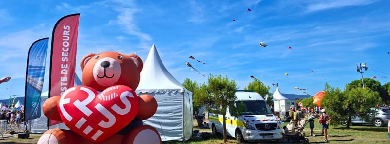 Festival International de l Air Frejus punct de prim ajutor Punct de prim ajutor la Festival International de l’Air Fréjus, marcat cu un urs gonflabil și amplasat lângă ambulanță, corturi și zonele cu zmeie din Base Nature.