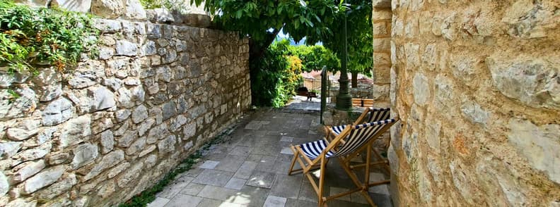 Alee umbrita Mons Var sat vechi Provence Franta Alee liniștită din Mons Var, între ziduri vechi din piatră, cu șezlonguri în dungi și umbră deasă sub copaci.