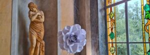 Villa Aurelienne Frejus ghid statuie floare si vitralii istorice Statuie clasică feminină, trandafir decorativ violet și fereastră cu vitralii colorate în interiorul Villa Aurélienne din Fréjus.