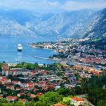 Kotor Hop On Hop Off Bus. Panoramic view of Kotor Bay Montenegro with cruise ship and red roof old town seen from above