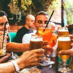 Pub Crawl in Sofia Bulgaria. Group of people clinking glasses of beer and cocktails inside a bar during a night out in Sofia