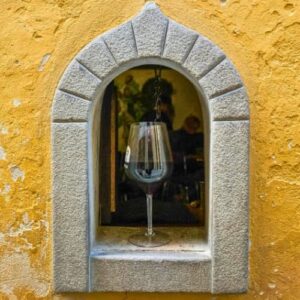 Florence sunset food tour photo. Wine glass framed by a stone window at sunset in Italy with warm evening light in Florence