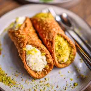Vatican food tour. Sicilian cannoli filled with ricotta and pistachio served on a plate during a Rome food tour