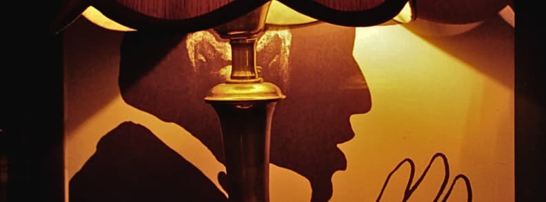 Radio Bar Tirana Prices and Vintage Interior Vintage lamp illuminating silhouetted profile artwork inside Radio Bar Tirana, with warm amber lighting and retro decor in Blloku.