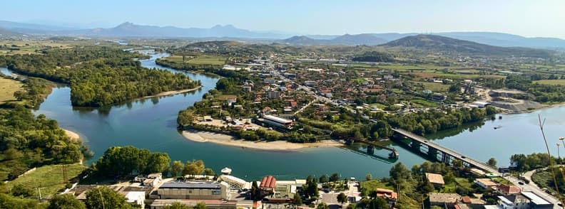 How to Get to Shkoder Albania Road and River Routes Panoramic view of the road approach to Shkodër, Albania, crossing rivers and green lowlands near Rozafa Castle, with hills and mountains in the distance.