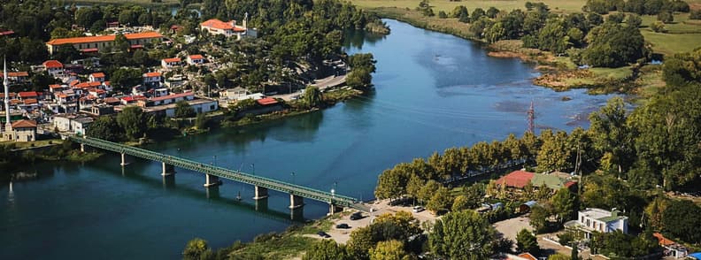 Is Shkoder Worth Visiting Albania City and River View Aerial view over Shkoder, Albania, with the Buna River, bridge, riverside neighborhoods, dense greenery, and farmland stretching beyond the city.