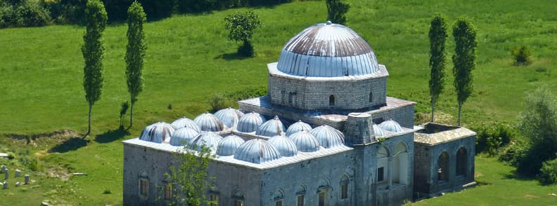 Shkoder Religious Landmarks Lead Mosque Albania Lead Mosque in Shkodër, Albania, with its large central dome, smaller domes, stone walls, and green fields surrounding the historic Ottoman religious site.