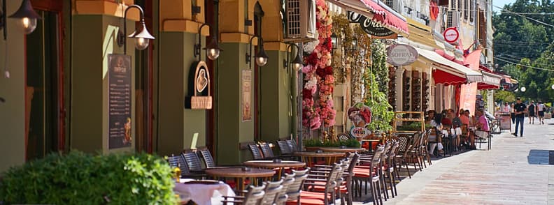 Where to Eat in Shkoder Albania Restaurant Guide Outdoor restaurant terraces lining a pedestrian street in central Shkoder, Albania, with café tables, colorful façades, and diners.