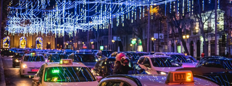 Traffic and taxis on a busy Madrid street at night under blue Christmas lights