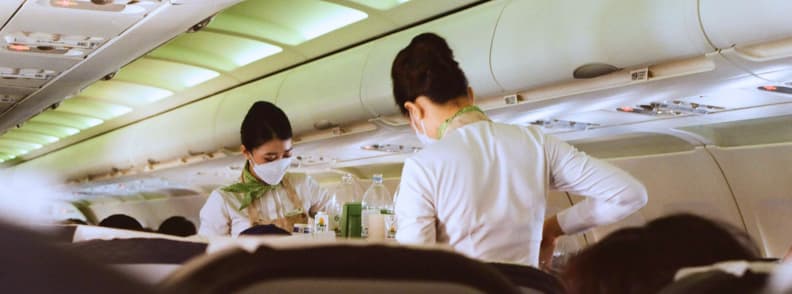 Staying Asleep Despite Disruptions Managing Cabin Announcements Sleep Interruptions Flight attendants serving drinks in the airplane aisle, illustrating how service and cabin announcements sleep interruptions can affect passengers trying to rest.