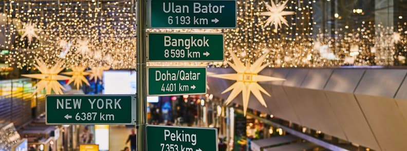Holiday airport signs showing global destinations and Christmas decorations above busy terminal