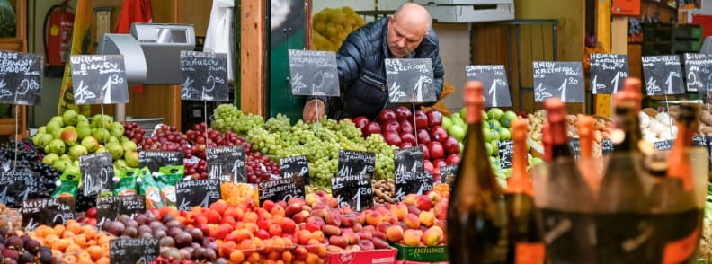 naschmarkt vienna winter fruit stalls local market Local vendor arranging fresh fruit at Naschmarkt in Vienna surrounded by colorful produce and price signs