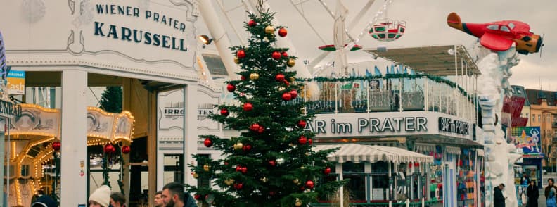 prater vienna winter rides carousel ferris wheel market Wiener Prater in winter with carousel, Christmas tree, and decorated amusement rides under cloudy skies