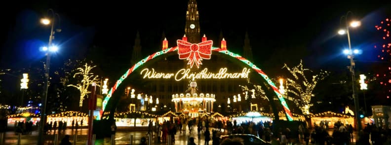 rathausplatz christmas market vienna festive lights Night view of Rathausplatz Christmas Market in Vienna with festive arch, glowing lights, and the illuminated City Hall in the background