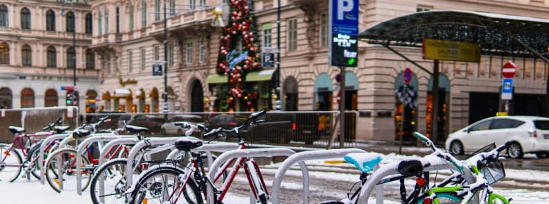 vienna winter street bikes snow christmas decorations Row of bicycles covered in light snow on a Vienna street with decorated Christmas tree and historic buildings in the background
