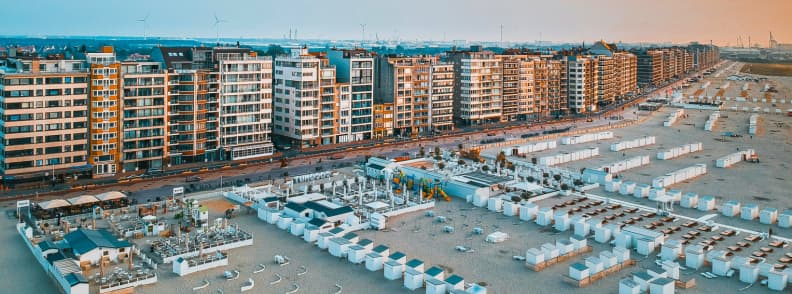 Aerial view of Knokke-Heist beachfront in Belgium with beach clubs, cabanas, and apartment buildings along Albertstrand at sunset