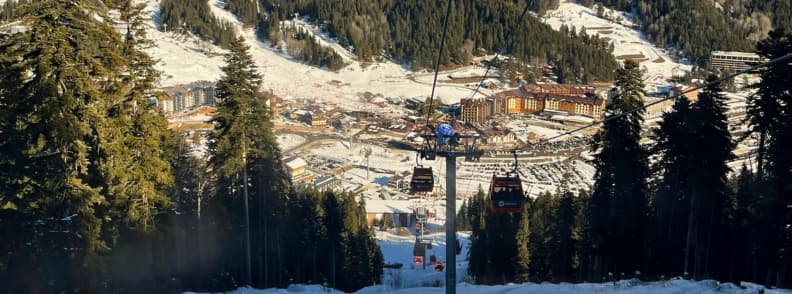 Bansko Gondola Winter View Bulgaria Ski Resort Guide Bansko Gondola cabins descending through a forest toward the Bansko ski resort village on a sunny winter day.