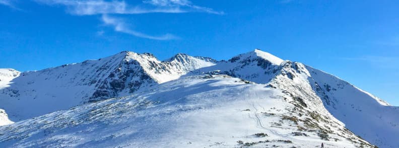 Borovets Bulgaria Rila Mountains Winter Ski Landscape Guide Snow covered ridge in Borovets with clear views of the surrounding Rila Mountains under a bright blue sky.
