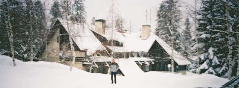 Insider Tips Skiing Bulgaria Local Advice and Expat Recommendations Snow covered lodge in Borovets Bulgaria ski resort with a winter forest behind it and a skier standing in front.