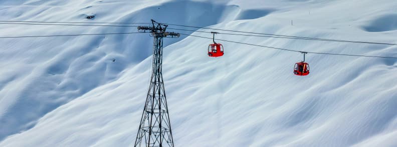 La Plagne French Ski Vocabulary Guide Two red gondolas crossing snowy terrain in La Plagne above smooth alpine slopes.