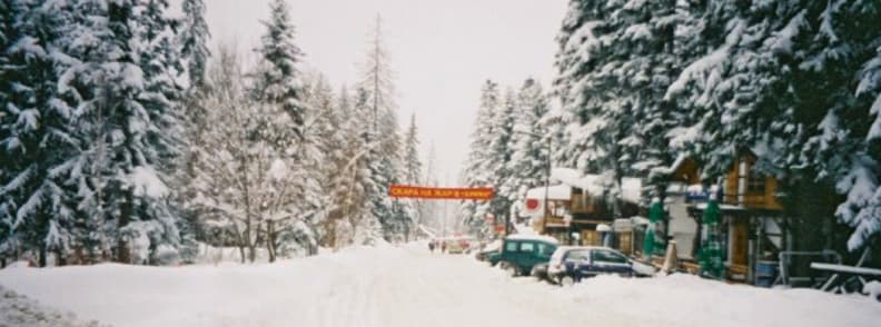 Practical Travel Information Bulgaria Ski Resorts Money Safety Connectivity Snow covered street lined with trees and small shops in Borovets Bulgaria ski resort during winter.