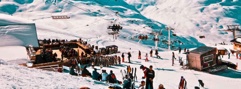 Skiing in France La Folie Douce Apres Ski Party Skiers gathering at La Folie Douce with chairs, music, and lively crowds on the slopes under bright Alpine sun.