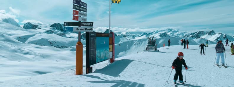 Skiing in France Tignes Grand Pre Panoramic Slopes Skiers at the Grand Pré sector in Tignes standing near piste signs with wide Alpine views and high altitude snowfields.