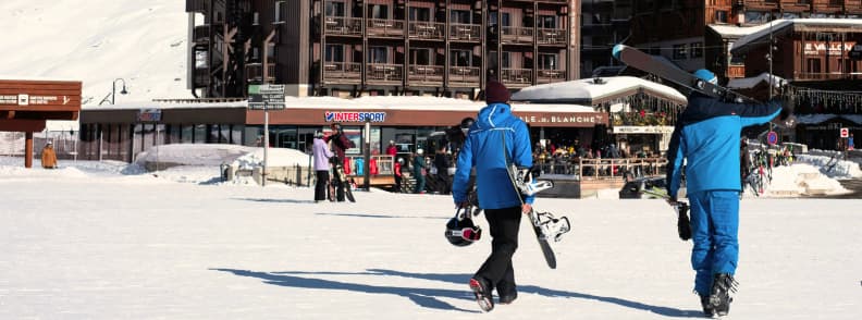 Tignes Apres Ski Guide Nightlife and Slope Bars Skiers walking through Tignes toward slope side bars and shops on a sunny winter day.