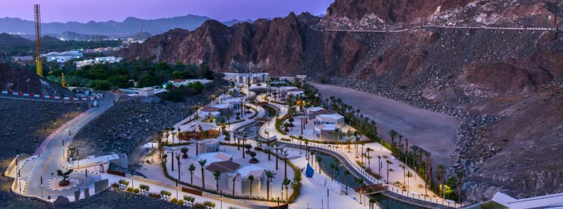 Hatta Wadi Park family outing with picnic areas and promenade UAE Aerial evening view of Hatta Wadi Park with walking paths, palm trees, and surrounding mountains