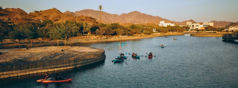 Swan Lake Hatta family friendly spot for picnics and birdwatching Kayakers on Swan Lake in Hatta UAE with mountains and greenery in the background