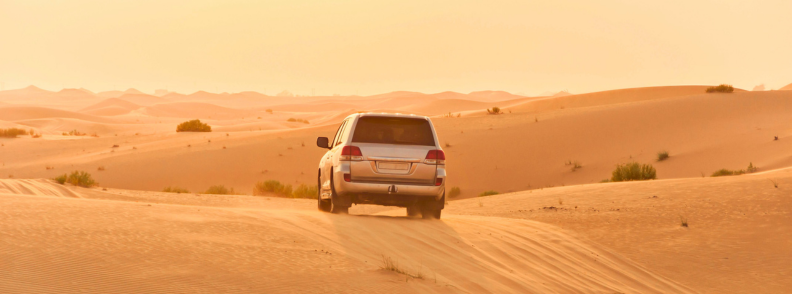 Desert safari Abu Dhabi cheap desert adventure SUV driving through golden sand dunes during a budget desert safari in Abu Dhabi